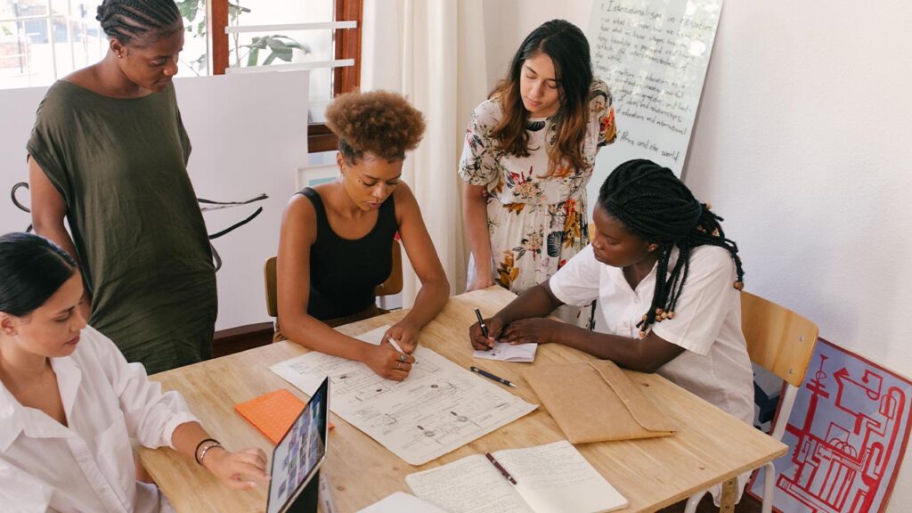 group of colleagues circled around a desk for a business meeting