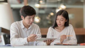 two people talking while looking at a tablet