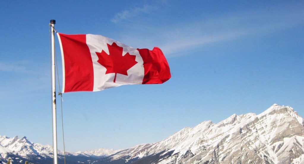the canadian flag over the rockies mountains
