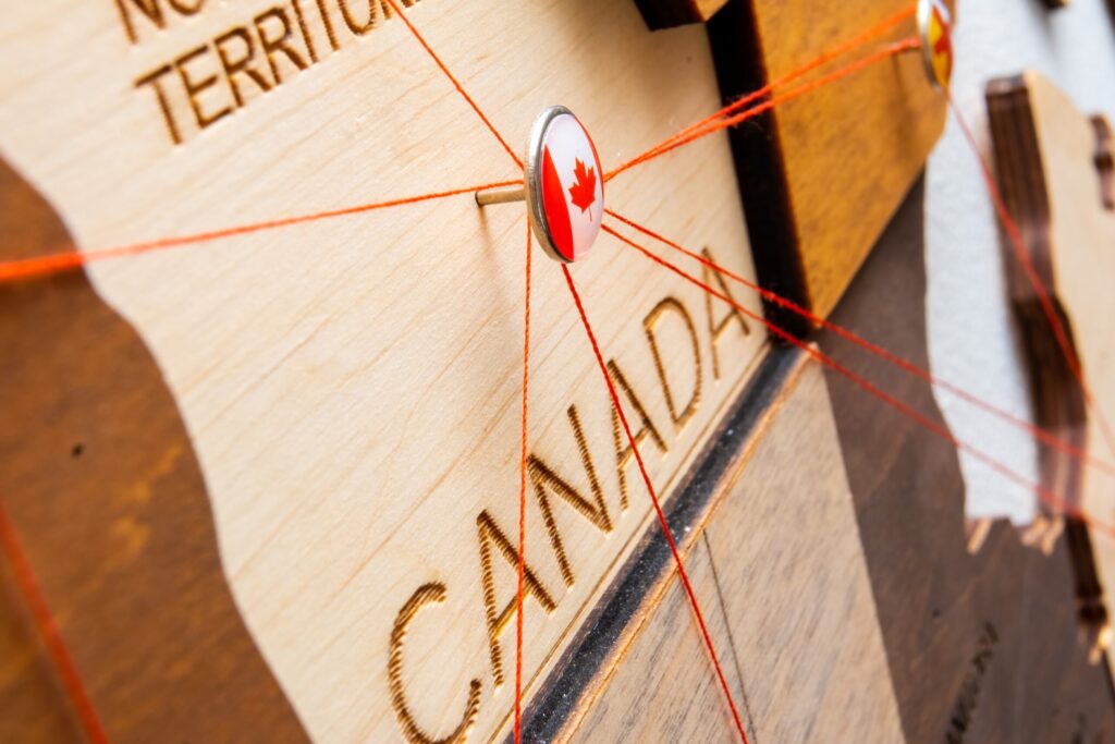 Close-up of a dartboard with a Canadian maple leaf flag pin hitting the center bullseye, with red laser targeting lines converging on the target, symbolizing the precision and focused approach required when entrepreneurs and investors strategically target the Canadian market for business opportunities, representing the accurate aim needed to successfully navigate financing decisions and achieve business goals in Canada's competitive economic landscape.