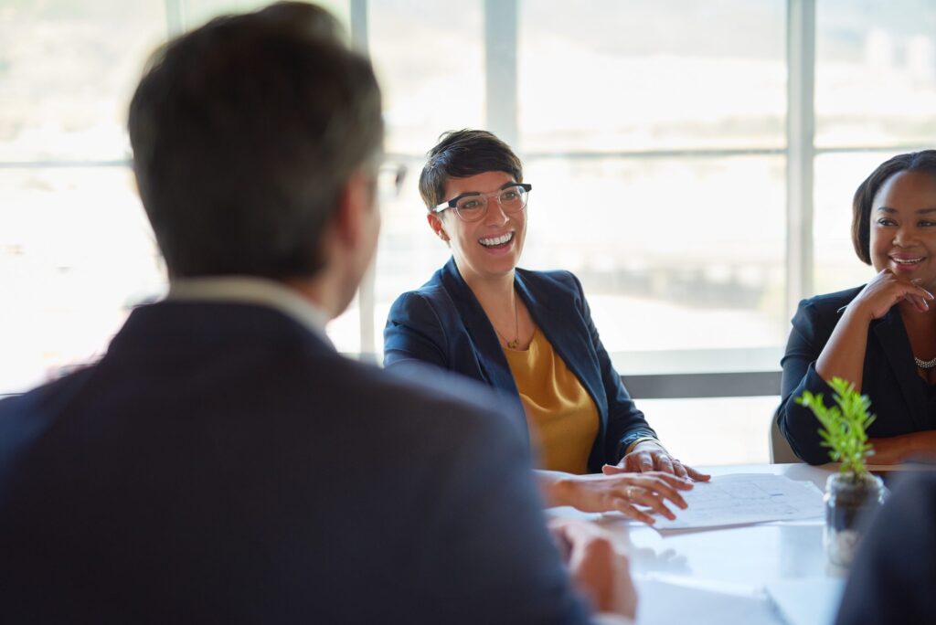 Business consultation meeting in a bright modern office where professionals discuss the search process to buy a business in Canada, with advisors helping clients evaluate potential acquisition opportunities by conducting thorough due diligence on target companies, reviewing financial files to assess the true cost and market value, while providing comprehensive service throughout the property and asset evaluation process to ensure informed decision-making when submitting a purchase request to the seller.