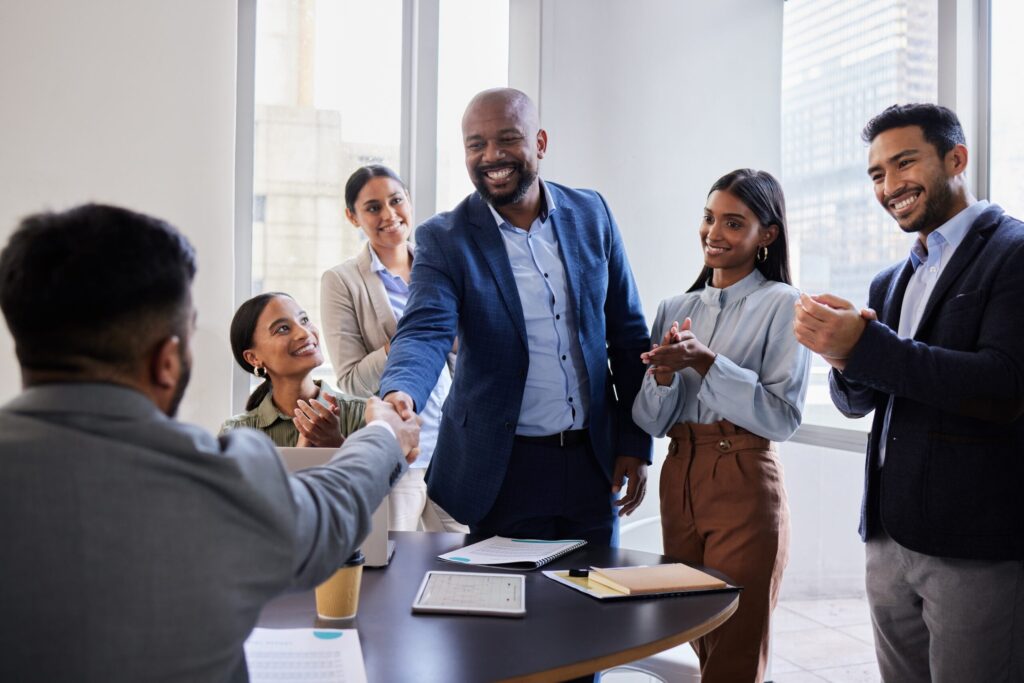Professional handshake between business parties in a modern office setting, representing the successful completion of a business sale in Canada where the buyer and seller have completed their due diligence process, evaluated the company's fixed assets and goodwill, negotiated the purchase price based on market conditions, and finalized financing arrangements, with legal and financial service providers facilitating the transaction through comprehensive file review and property transfer documentation, ensuring both parties achieve their business objectives in the Canadian market through this acquisition.