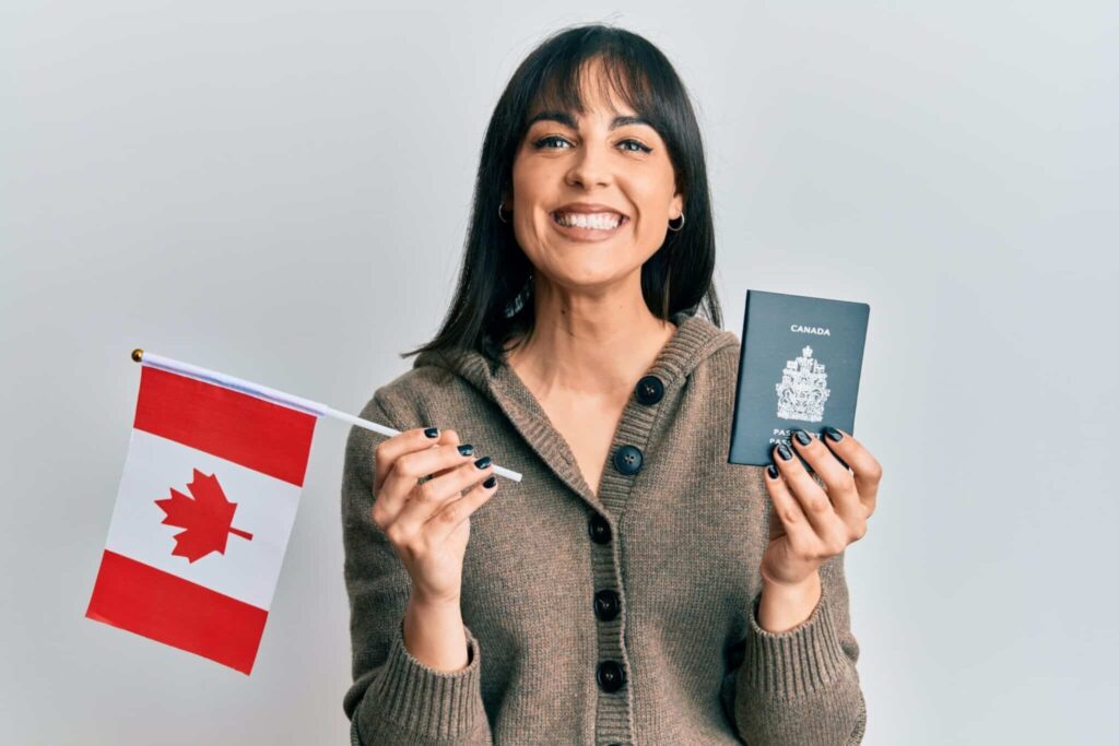 Smiling person holding a Canadian passport and flag representing successful immigration and citizenship approval in 2025
