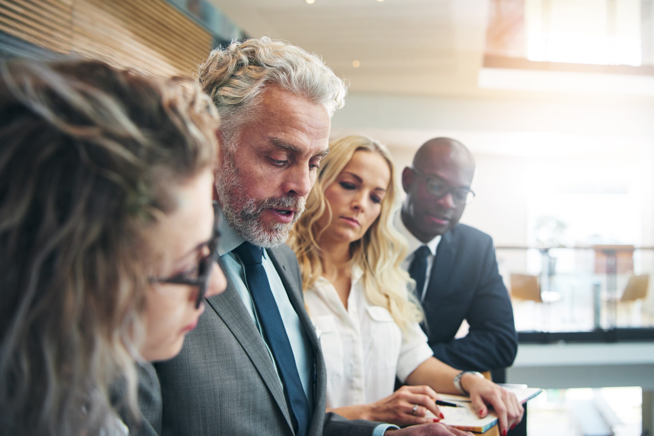 Multiracial office workers communicating and collaborating in a modern workplace, reflecting Canada’s diverse population and the collaborative spirit of immigrant entrepreneurship across regions.