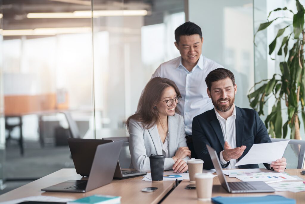 Foreign entrepreneurs review a business plan together, exploring business immigration programs like the provincial nominee program for entrepreneurs to start a new or existing business in Canada and gain permanent residence.