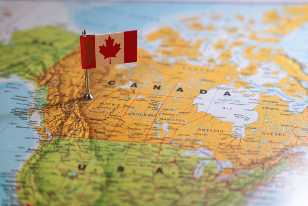 A red pin marks a location on the Canadian political map, representing a target destination for business establishment through business immigration programs. Foreign nationals planning to start a business in provinces like British Columbia or Quebec can benefit from strategic projects and regional stream initiatives that support economic growth and permanent residence.