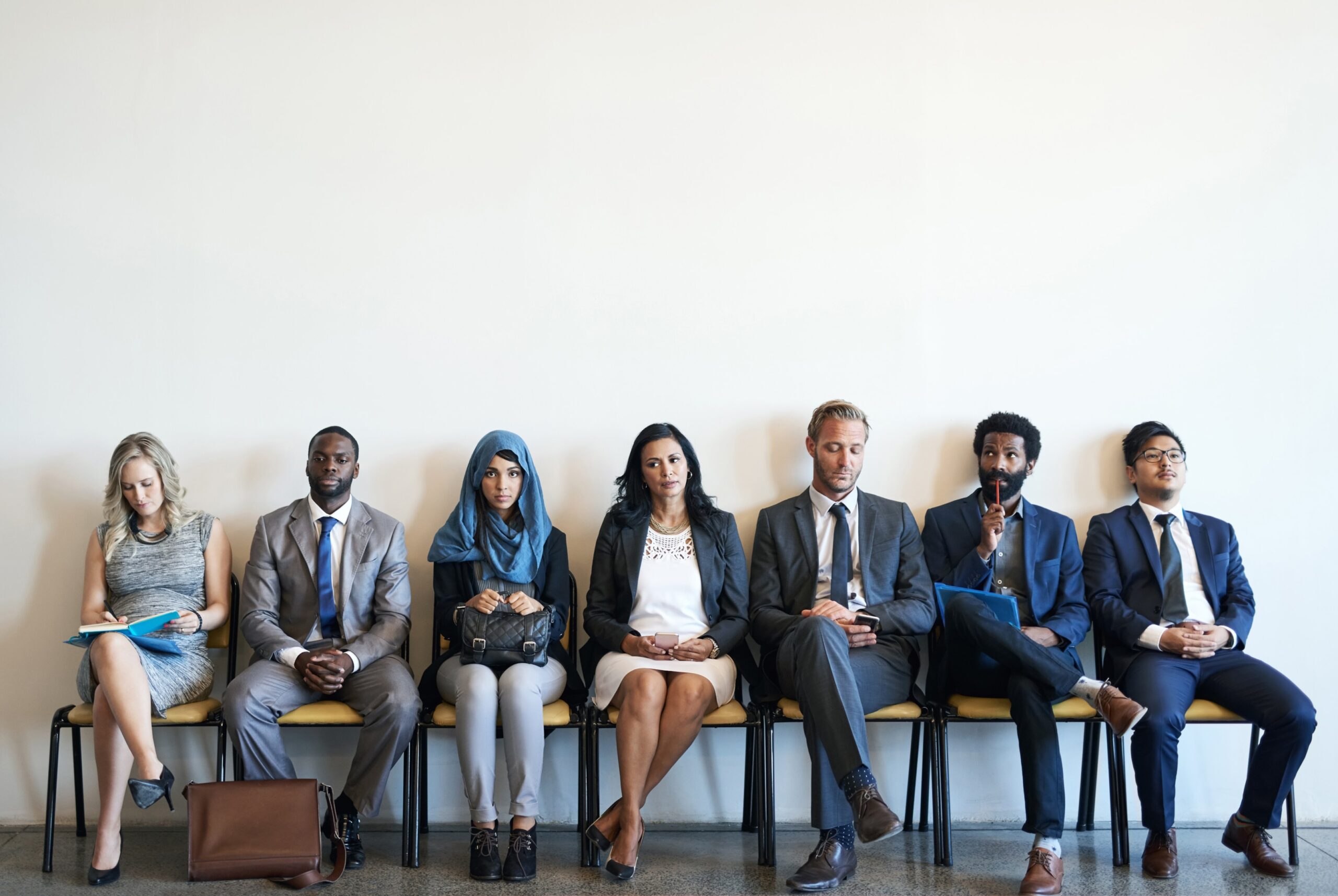 International candidates from diverse backgrounds await their turn in a recruitment setting, highlighting foreign workers with international experience seeking faster processing through Canada's employer-specific work permit streams.