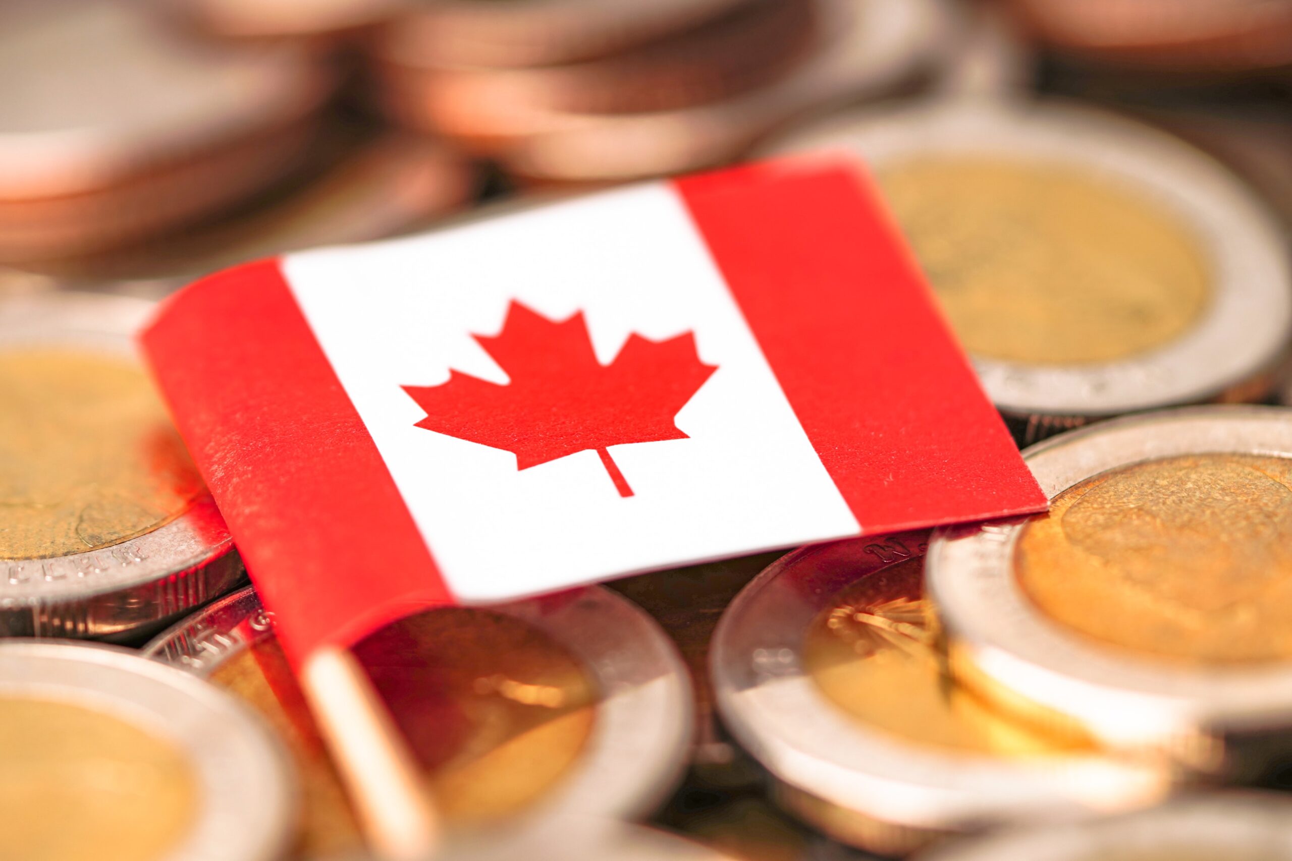 Canadian coins in front of the national flag symbolize financial planning, tax considerations, and the legal benefits of operating a business or corporation in Canada.