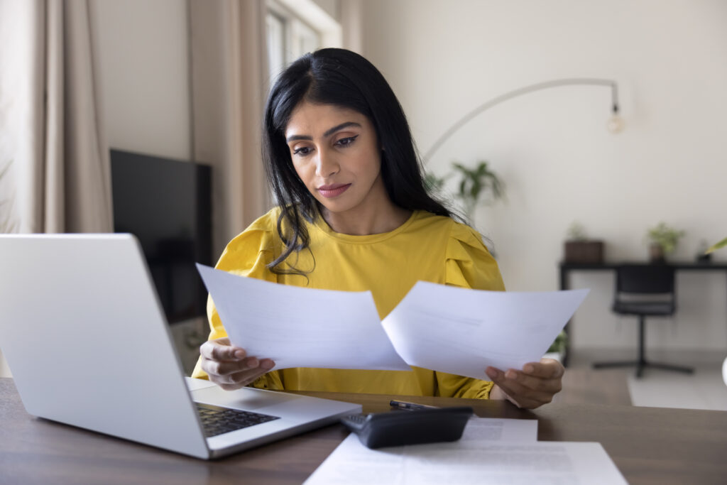A businesswoman reviewing documents at her desk, preparing a strategy to shift from an ICT to a C11 work permit, highlighting her company’s ongoing efforts and contributions to Canada.
