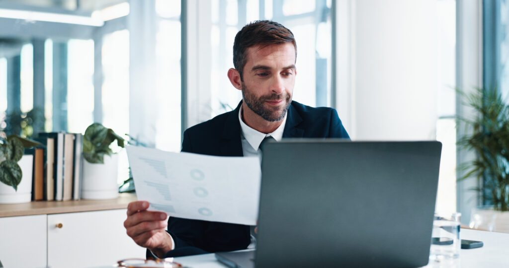The same entrepreneur, now confident, reviews comprehensive business plans and financial requirements on a laptop, showing progress in aligning with business immigration pathways and the Canadian market.