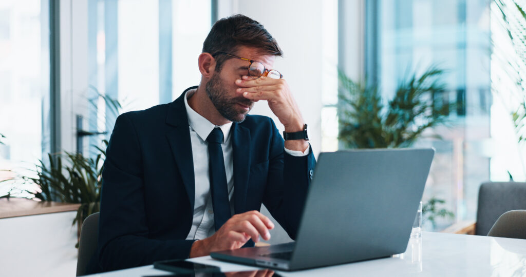 A disappointed startup entrepreneur sits in front of a laptop after setbacks with their minimum viable product and business operations, concerned about their permanent resident status and immigration process.