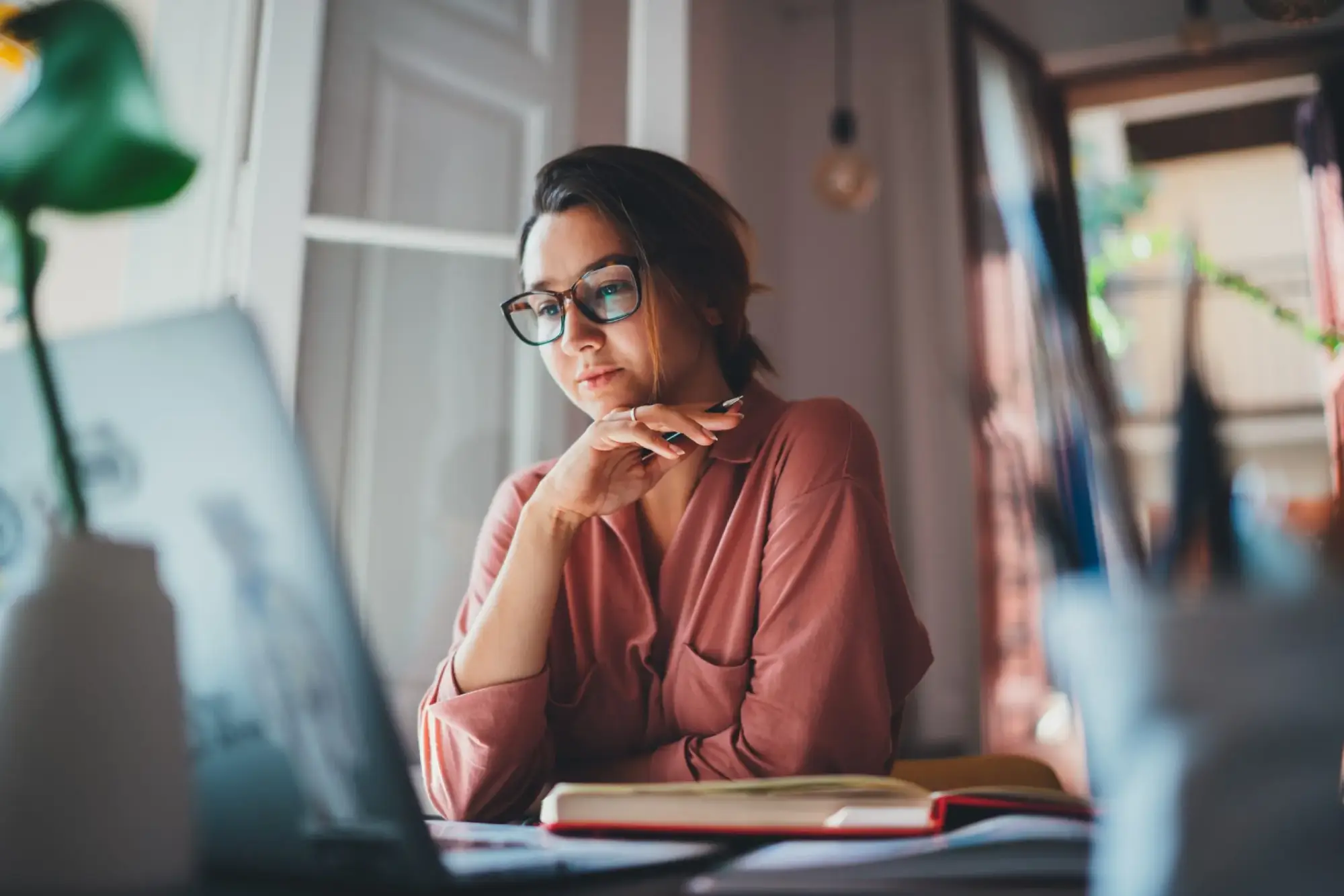 Focused woman reviewing documents on her laptop while working remotely, representing professional legal or business consultation.