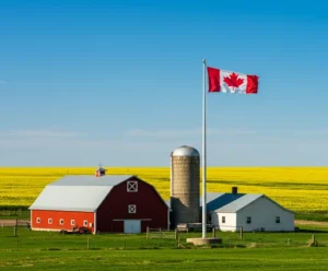Canadian farm with red barn, grain silo, and national flag on a sunny day.