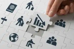 A hand places a puzzle piece with a declining bar graph icon into a puzzle surrounded by symbols of travel, people, the globe, SUV approval rate, a passport, and business—highlighting interconnected aspects of global issues.